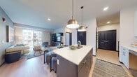 Located at 2074 Fox Valley Center in Aurora, IL, this thoughtfully designed single-floor residence combines modern aesthetics with functional living. The open-concept layout seamlessly connects the kitchen and living area, creating a bright, welcoming atmosphere enhanced by recessed lighting and light wood-style flooring.

The kitchen is a standout feature, outfitted with two-tone cabinetry — white upper cabinets paired with darker lower units — quartz countertops, a subway tile backsplash, and a full suite of stainless steel appliances including a gas range, built-in microwave, dishwasher, and French door refrigerator. A central island with pendant lighting serves as both a prep space and casual dining area. A chalkboard wall near the entry adds a playful, functional touch.

The living area offers generous space with large windows that invite natural light. Two bedrooms provide comfortable retreats; the primary bedroom features large windows with outdoor views and a walk-in closet with a frosted glass sliding door. The secondary bedroom is versatile and well-lit. The bathroom is finished with floor-to-ceiling tile surrounds and a soaking tub-shower combination. Throughout, the design balances contemporary style with everyday practicality.
