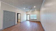 This single-floor unit offers a thoughtfully designed open-concept layout that seamlessly connects the kitchen and living areas. The living space features warm hardwood-style flooring, crown molding, and elevated ceilings accented by recessed lighting and a ceiling fan. A window fitted with blinds allows natural light to fill the room while providing outdoor views.

The kitchen is a standout feature, equipped with dark espresso cabinetry, a gray subway tile backsplash, and a suite of stainless steel appliances including a range, microwave, and refrigerator. A central island with a speckled quartz countertop and a double stainless steel sink serves as a functional focal point, illuminated by stylish pendant lights overhead. Ample cabinet storage is also available nearby via a large closet adjacent to the kitchen.

The bathroom includes a glass-enclosed walk-in shower with large-format tile surround, a quartz-topped vanity with dark cabinetry, and direct access to a dedicated in-unit laundry room housing a full-sized washer and dryer. The bedroom offers plush carpeting and a clean, neutral palette, providing a comfortable and quiet retreat.
