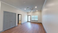 This single-floor unit offers a thoughtfully designed open-concept layout that seamlessly connects the kitchen and living areas. The living space features warm hardwood-style flooring, crown molding, and elevated ceilings accented by recessed lighting and a ceiling fan. A window fitted with blinds allows natural light to fill the room while providing outdoor views.

The kitchen is a standout feature, equipped with dark espresso cabinetry, a gray subway tile backsplash, and a suite of stainless steel appliances including a range, microwave, and refrigerator. A central island with a speckled quartz countertop and a double stainless steel sink serves as a functional focal point, illuminated by stylish pendant lights overhead. Ample cabinet storage is also available nearby via a large closet adjacent to the kitchen.

The bathroom includes a glass-enclosed walk-in shower with large-format tile surround, a quartz-topped vanity with dark cabinetry, and direct access to a dedicated in-unit laundry room housing a full-sized washer and dryer. The bedroom offers plush carpeting and a clean, neutral palette, providing a comfortable and quiet retreat.
