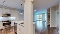 This well-appointed 2-bedroom, 2-bathroom residence in King of Prussia, PA offers a thoughtfully designed single-floor layout with modern finishes throughout. The open-concept kitchen and living area forms the heart of the home, featuring rich hardwood flooring, a kitchen island with granite countertops, white shaker cabinetry, stainless steel appliances, a tile backsplash, and pendant lighting. Large windows in the living area flood the space with natural light and provide views of the surrounding greenery, with direct access to a private balcony. The primary bedroom is generously sized with plush carpeting, multiple windows, and an en-suite bathroom complete with a dual-sink vanity topped with granite counters, white cabinetry, large-format tile flooring, a walk-in shower, and a spacious walk-in closet with built-in shelving. The second bedroom is equally well-lit with soft carpet and ample natural light. A dedicated laundry room houses a full-size washer and dryer alongside built-in cabinetry for added storage. Two closets provide organizational flexibility throughout the residence, while a connecting hallway ties the layout together seamlessly.
