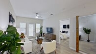 This single-floor residence offers a thoughtfully designed layout that balances open-concept living with defined private spaces. The living room serves as the heart of the home, featuring light-toned luxury vinyl plank flooring, neutral gray-white walls, and a ceiling fan overhead. Large windows and a glass-paned exterior door invite abundant natural light, while direct access to an outdoor area enhances the sense of openness.

The kitchen is well-equipped with stainless steel appliances, including a refrigerator, electric range, microwave, and dishwasher. White upper cabinetry contrasts with gray lower cabinets, complemented by white quartz countertops and a subway tile backsplash. A peninsula with bar seating provides a casual dining option and connects the kitchen to the main living area. A distinctive reclaimed wood accent post adds a warm, rustic touch near the kitchen entrance.

Both bedrooms are generously sized, each featuring ceiling fans, wide windows with blinds, and ample natural light. The primary bedroom benefits from direct access to a walk-in closet outfitted with built-in shelving for organized storage. The full bathroom includes a double-sink vanity with gray cabinetry, a soaking tub with tile surround accented by a mosaic tile border, and stone-look tile flooring throughout.