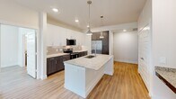 Located at 8801 Old Hickory Trail in Dallas, TX, this single-story 2-bedroom, 3-bathroom home offers a thoughtfully designed layout with modern finishes throughout. Light wood-look flooring flows seamlessly across the open-concept living areas, creating a warm and cohesive aesthetic.

The kitchen is a standout feature, showcasing a large center island with granite countertops and a stainless steel sink, complemented by pendant lighting overhead. Two-toned cabinetry — white uppers paired with dark wood lower cabinets — frames a tile backsplash and a full suite of stainless steel appliances, including a French door refrigerator, range, and built-in microwave.

Both bedrooms are bright and airy, benefiting from natural light through large windows with outdoor greenery views, and are served by dedicated closets with built-in shelving. The primary bedroom connects directly to a well-appointed bathroom featuring a double-sink granite vanity, a glass-enclosed walk-in shower with floor-to-ceiling tile, and wood-look flooring.

Additional bathrooms maintain the same clean, contemporary design. The home also includes two dedicated closet spaces for ample storage. Outside, a private yard enclosed by a wrought iron fence opens to a serene backdrop of mature trees, offering a peaceful outdoor retreat.