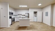 Located at 7750 Belfort Pkwy in Jacksonville, FL, this 2-bedroom, 2-bathroom residence is designed with a clean, modern aesthetic and a practical single-floor layout. Wood-look tile flooring runs consistently throughout the home, lending a cohesive and contemporary feel to every room.

The kitchen is a standout feature, offering white shaker-style cabinetry, a subway tile backsplash, light stone countertops, and a full suite of stainless steel appliances including a range, microwave, dishwasher, and refrigerator. A center island provides additional prep and counter space. A dedicated laundry closet with a washer and dryer is conveniently accessible just off the kitchen area.

The living area is bright and open, featuring a ceiling fan and French doors that lead to an outdoor balcony, allowing for natural light and outdoor views. Both bedrooms are well-proportioned, each equipped with ceiling fans and windows that bring in natural light.

The two bathrooms are finished with white vanity cabinetry, stone-toned countertops, and tile surround. One bathroom includes a soaking tub, while the second offers a shower. The hallways are clean and well-lit, contributing to the overall open feel of the home. The unit also includes an electrical panel conveniently located in the main corridor.