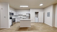 Located at 7750 Belfort Pkwy in Jacksonville, FL, this 2-bedroom, 2-bathroom residence is designed with a clean, modern aesthetic and a practical single-floor layout. Wood-look tile flooring runs consistently throughout the home, lending a cohesive and contemporary feel to every room.

The kitchen is a standout feature, offering white shaker-style cabinetry, a subway tile backsplash, light stone countertops, and a full suite of stainless steel appliances including a range, microwave, dishwasher, and refrigerator. A center island provides additional prep and counter space. A dedicated laundry closet with a washer and dryer is conveniently accessible just off the kitchen area.

The living area is bright and open, featuring a ceiling fan and French doors that lead to an outdoor balcony, allowing for natural light and outdoor views. Both bedrooms are well-proportioned, each equipped with ceiling fans and windows that bring in natural light.

The two bathrooms are finished with white vanity cabinetry, stone-toned countertops, and tile surround. One bathroom includes a soaking tub, while the second offers a shower. The hallways are clean and well-lit, contributing to the overall open feel of the home. The unit also includes an electrical panel conveniently located in the main corridor.