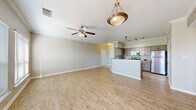 This thoughtfully designed 2-bedroom, 2-bathroom single-floor residence offers a comfortable and functional layout with consistent light wood-style flooring flowing throughout the entire space. The open-concept kitchen and living area serves as the heart of the home, featuring a peninsula with a pendant light fixture, taupe cabinetry, stainless steel appliances including a refrigerator and microwave, and track lighting above the kitchen zone. The living area is generously proportioned, accented by crown molding, a ceiling fan, and large windows fitted with horizontal blinds that allow abundant natural light to fill the space. The primary bedroom is a well-sized retreat with its own ceiling fan, a window with natural light, and access to a spacious walk-in closet outfitted with wire shelving systems for organized storage. The second bedroom is comparably appointed, also featuring a ceiling fan and a bright window. Both bathrooms are cleanly finished, with one featuring a soaking tub and shower combination with tile surround and overhead cabinetry. Additional highlights include an in-unit laundry room, two closets, and a connecting hallway that ties the layout together efficiently. Neutral wall tones and clean white trim complete the fresh, move-in-ready aesthetic throughout.