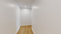 Located on the fifth floor at 337-339 Johnston Ave in Jersey City, NJ, this thoughtfully designed one-bedroom, one-bathroom residence offers a clean, contemporary aesthetic throughout. Light-toned hardwood flooring runs continuously across the entire unit, lending warmth and visual cohesion to every room.

The open-concept kitchen and living area serves as the heart of the home. The kitchen is outfitted with white shaker-style cabinetry, quartz countertops, a subway tile backsplash, stainless steel appliances including a gas range and refrigerator, and a deep undermount sink with a matte black faucet. Gold-toned globe pendant lights add a refined accent. A large central island provides additional prep space and casual seating.

The living area is bathed in natural light from expansive floor-to-ceiling corner windows that frame sweeping views of the Jersey City skyline and surrounding neighborhood. The bedroom offers a comfortable footprint and features a set of double doors leading to ample closet storage, complemented by a second closet elsewhere in the unit.

The bathroom is finished with large-format neutral floor tiles, a soaking tub with tiled surround, and matte black fixtures and hardware throughout. An in-unit laundry area adds everyday convenience. The hallway connects all spaces efficiently, completing this well-appointed urban residence.