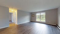 This single-floor residence in Amherst, Massachusetts offers a well-organized layout with a clear separation between living and sleeping areas. The spacious main living area features light-toned hardwood-style flooring and neutral gray walls, creating a bright and versatile setting. Large multi-pane windows allow abundant natural light and frame views of surrounding greenery, enhancing the open feel of the space. Baseboard heating runs throughout, providing consistent warmth.

The galley-style kitchen is outfitted with white shaker cabinets, granite-patterned countertops, stainless steel appliances including a refrigerator and electric range, and a stainless steel sink — offering a clean, functional workspace.

The bedrooms are carpeted for comfort and finished with the same neutral palette. Each room includes a sliding-door closet for ample storage, and windows provide natural light and outdoor views. One bedroom features a double sliding closet and direct access to the hallway.

The bathroom is finished with light wood-style flooring, a tub/shower combination with tiled surround, a single vanity with modern fixtures, and a well-lit mirror — maintaining the clean aesthetic found throughout the unit.