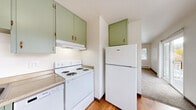 This 2-bedroom, 1-bathroom unit offers a practical and well-organized layout across a single floor. The living area is bright and open, featuring neutral carpet, white walls, a textured ceiling, and a sliding glass door that leads to a private balcony overlooking the surrounding complex. A second window allows additional natural light to fill the space. A baseboard heating system runs throughout, providing consistent warmth.

The kitchen is a standout with its distinctive sage green cabinetry, warm hardwood floors, and white appliances including a coil-top range, dishwasher, and full-size refrigerator. A window over the sink area adds natural light, while ample upper and lower cabinet storage keeps the space functional.

Both bedrooms are carpeted and feature ceiling fans with light fixtures, closets, and windows that bring in outdoor views. The primary bedroom is generously sized and includes a dedicated closet. Across the unit, four closets in total provide plentiful storage.

The bathroom is clean and well-appointed, with a full soaking tub and shower combination, a dark wood vanity with a modern mirror, hardwood flooring, and a high window for privacy and ventilation. The unit's straightforward design and efficient use of space make it a highly practical residence.