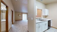 Located at 3524 Fifth St W in West Fargo, North Dakota, this two-bedroom, one-bathroom unit offers a practical and comfortable single-floor layout. The open living area is highlighted by soaring vaulted ceilings and recessed lighting, creating an airy, spacious feel. Plush carpeting extends throughout the living and bedroom areas, while a sliding glass door floods the living room with natural light and provides access to a private outdoor area. Vertical blinds offer privacy control.

The kitchen features white cabinetry, a double-basin sink, and a pass-through window that connects seamlessly to the living space, enhancing the open-concept feel. Appliances including a refrigerator and microwave are visible from the living area.

The generously sized primary bedroom offers ample room, a large window with blinds for natural light, and a baseboard heating unit. The second bedroom is bright and carpeted, with neutral wall tones throughout. The full bathroom is finished with tile flooring, a white vanity with an integrated sink, a large mirror, and towel bars.

A dedicated laundry room with tile flooring houses a full-size washer and dryer alongside wire shelving for storage. A closet provides additional organizational space, completing this well-appointed home.
