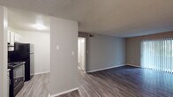 Located at 461 Forest Hill Rd in Macon, Georgia, this single-floor residence offers a clean, updated interior with a neutral gray color palette throughout. The living areas feature durable wood-look flooring and textured ceilings, creating a bright and cohesive atmosphere. The open layout connects the living space to the kitchen, which is equipped with white cabinetry, granite-style countertops, a double stainless steel sink with a modern brushed nickel faucet, a classic subway tile backsplash, and black appliances including a range with overhead ventilation. The bedrooms are carpeted for comfort and include ceiling fans with lighting. The primary bedroom is particularly well-appointed, offering dual closets with built-in shelving for generous storage. Additional bedrooms also feature closet space and natural light from windows with blinds. A sliding glass door in one room provides outdoor access and fills the space with natural light. The bathroom is neatly finished with wood-look flooring, a single vanity, and a full tub-shower combination. Throughout the unit, clean white trim, ample wall space, and thoughtful layout make this a practical and comfortable residence.