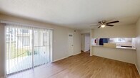 This single-story, 2-bedroom, 1.5-bathroom residence in Gretna, Louisiana offers a practical and comfortable layout throughout. The living area is bright and open, featuring wood-style flooring, a ceiling fan, and a full-width sliding glass door fitted with vertical blinds that fills the space with natural light and provides access to an outdoor area. A pass-through counter connects the living space to the kitchen, enhancing the open feel.

The galley-style kitchen is efficiently designed with white cabinetry, granite-look countertops, and a suite of appliances including a stainless steel refrigerator, black electric range with overhead microwave, and dishwasher. A window above the counter adds additional natural light. A central hallway connects the main living areas to both bedrooms and bathrooms.

Both bedrooms feature plush carpeting and ceiling fans, with windows that bring in natural light. The full bathroom includes a tiled tub-shower combination, while the half bathroom provides a vanity with a granite-look countertop and medicine cabinet. Textured ceilings are found throughout, contributing to the unit's consistent, neutral aesthetic.