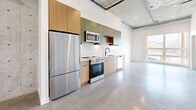 Located at 660 S 400 W in Salt Lake City, Utah, this one-bedroom, one-bathroom unit offers a thoughtfully designed industrial-modern aesthetic throughout. Polished concrete floors and exposed concrete ceilings with visible ductwork and sprinkler piping define the space's urban character, while crisp white walls keep the atmosphere bright and contemporary.

The open-concept main living area seamlessly integrates the kitchen, dining, and living spaces into one cohesive room. The well-appointed kitchen features a full suite of stainless steel appliances—including a refrigerator, electric range, microwave, and dishwasher—paired with two-tone cabinetry in natural wood and muted green tones, light quartz countertops, and a white subway tile backsplash. Large windows in the living area invite abundant natural light and provide views of the surrounding neighborhood.

The bedroom is accessed via a sleek sliding door and offers a comfortable, private retreat. Three closets throughout the unit provide generous storage options, each featuring rod and shelf systems. The bathroom is finished with polished concrete flooring, a soaking tub and shower with white tile surround, matte black fixtures, built-in open shelving, and a wood-accented vanity with a quartz countertop. The unit's cohesive design and efficient layout make it a compelling urban living option.