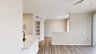 This 650 square foot, one-bedroom, one-bathroom apartment at Lakeline Villas in Cedar Park, TX offers a well-designed single-floor layout with modern finishes throughout. The open-concept kitchen and living area serves as the heart of the unit, featuring a large white quartz peninsula with an undermount sink and matte black faucet, crisp white shaker cabinetry, a subway tile backsplash, and stainless steel appliances including a refrigerator, electric range, and built-in microwave. Light wood-look plank flooring runs throughout the entire unit, adding warmth and cohesion. The living room is bright and inviting, with a ceiling fan, crown molding, and sliding glass doors that open to an outdoor space with lush greenery views. The 180 square foot primary bedroom is spacious and well-lit, offering a ceiling fan, a large window for natural light, and access to two closets, including a walk-in. The bathroom is finished with white shaker vanity cabinetry, a quartz countertop, a framed mirror, matte black fixtures, and a tiled shower-tub combination. Neutral warm-toned walls and clean white trim complete the polished, move-in-ready aesthetic of this Cedar Park apartment.