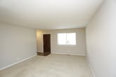 This thoughtfully laid-out space is spread across three floors, offering a versatile and functional layout suited to a variety of living arrangements. The interior design embraces a neutral, understated palette, with smooth white ceilings and light beige walls that create a bright, airy atmosphere throughout.

The living area is generously proportioned, featuring wall-to-wall neutral carpeting that adds warmth and comfort underfoot. The open layout allows for flexible furniture arrangements, making the space feel both expansive and welcoming. Clean white baseboards frame the room, contributing to the overall crisp and tidy appearance.

Natural light plays a key role in the ambiance of this space. A glass door or large window at the far end of the living area allows daylight to filter in, illuminating the interior and creating a seamless connection between the indoors and the outside. An elegant chandelier serves as a focal point in the adjoining area, adding a subtle touch of refinement to the otherwise minimalist design.

The transition between rooms is smooth and open, with the layout encouraging natural flow from one area to the next. The multi-floor configuration provides ample opportunity for defined living, sleeping, and utility zones, making this a highly practical and adaptable space.