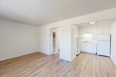 Located at 1515 S Novato Blvd in Novato, California, this one-bedroom, one-bathroom single-floor unit offers a well-organized and efficient layout with consistent light wood-look flooring and crisp white walls throughout. The open-concept living and dining area provides a spacious, versatile gathering space, with a large window inviting natural light and views of the landscaped surroundings, as well as a sliding glass door fitted with vertical blinds for additional outdoor access and light control. Textured popcorn ceilings add a classic character to the space. The kitchen is efficiently designed with white cabinetry offering ample storage, light-toned countertops, a double-coil electric range, a full-size refrigerator, and a single-basin sink — all finished in a cohesive white palette. The bedroom is a comfortable size, featuring a mirrored sliding-door closet and additional closet storage. The bathroom is clean and functional, with a vanity featuring under-sink cabinetry, a medicine cabinet with mirror, and contemporary black hardware accents. A hallway connects the main living areas to the private spaces. The unit is set amid mature trees, contributing to a peaceful residential atmosphere.