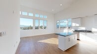 Located at 771 W Hamilton Ave in Campbell, CA, this single-floor residence showcases a contemporary design characterized by soaring ceilings, crisp white walls, and an abundance of natural light throughout. The open-concept living and kitchen area serves as the heart of the space, where expansive floor-to-ceiling windows and transom windows above frame sweeping views of the surrounding mountains and cityscape, creating an airy, elevated atmosphere. Hardwood-style flooring flows throughout the main living areas, adding warmth to the modern aesthetic.

The kitchen is well-appointed with white shaker cabinetry reaching toward the ceiling, dark countertops, a central island with additional storage, and a full suite of stainless steel appliances including a gas range, built-in microwave, dishwasher, and refrigerator. Generous counter space and ample cabinetry make this a highly functional cooking environment.

The bedrooms feature plush carpeting and large windows that continue the theme of natural light and outdoor views. Bathrooms are finished with clean, modern fixtures, including a shower-tub combo with sliding glass doors and a separate walk-in shower in the second bath. The overall ambiance is bright, clean, and contemporary throughout.