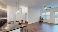 This 2-bedroom, 2-bathroom residence in Columbia, SC offers a thoughtfully designed open-concept layout that seamlessly connects the kitchen and living areas. The kitchen is a standout feature, showcasing dark espresso cabinetry, granite countertops with a decorative tile backsplash, and stainless steel appliances including a refrigerator, range, and built-in microwave. A central island with pendant lighting provides additional prep space and casual seating for two. Rich dark hardwood flooring extends throughout the main living area, complemented by crown molding and a ceiling fan, while large windows and a glass door invite natural light and outdoor views into the living room. Both bedrooms are carpeted and generously sized, each served by its own full bathroom. The bathrooms feature dark vanity cabinetry, tile flooring, and shower-tub combinations. Two dedicated closets provide ample storage throughout the home. The overall ambiance is clean, modern, and inviting, with a neutral color palette that creates a bright and versatile living environment well-suited for a variety of lifestyles.