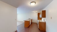 This single-floor, 2-bedroom, 1-bathroom unit offers a practical and efficient layout across a comfortable footprint. The kitchen serves as a functional centerpiece, featuring warm oak cabinetry, a peninsula with a built-in sink and dishwasher, laminate countertops, and white appliances including a range, microwave, and refrigerator. Hardwood-style flooring runs throughout the kitchen, creating a clean transition into the adjacent living room, which is carpeted and illuminated by a large window with vertical blinds, allowing natural light to fill the space. A baseboard heating unit and wall-mounted air conditioner provide year-round climate control in the living area.

Both bedrooms are carpeted and feature ceiling fans with integrated lighting. Each bedroom includes a window with exterior views and baseboard heating. The primary bedroom offers a wide double closet with bifold doors, built-in shelving, and hanging rods, providing generous storage. The full bathroom includes a tiled tub-shower combination with a curved curtain rod, a wood-toned vanity, and stone-look tile flooring. The unit is completed by a dedicated entrance and an additional closet, contributing to the overall practicality of the layout.