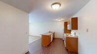 This single-floor, 2-bedroom, 1-bathroom unit offers a practical and efficient layout across a comfortable footprint. The kitchen serves as a functional centerpiece, featuring warm oak cabinetry, a peninsula with a built-in sink and dishwasher, laminate countertops, and white appliances including a range, microwave, and refrigerator. Hardwood-style flooring runs throughout the kitchen, creating a clean transition into the adjacent living room, which is carpeted and illuminated by a large window with vertical blinds, allowing natural light to fill the space. A baseboard heating unit and wall-mounted air conditioner provide year-round climate control in the living area.

Both bedrooms are carpeted and feature ceiling fans with integrated lighting. Each bedroom includes a window with exterior views and baseboard heating. The primary bedroom offers a wide double closet with bifold doors, built-in shelving, and hanging rods, providing generous storage. The full bathroom includes a tiled tub-shower combination with a curved curtain rod, a wood-toned vanity, and stone-look tile flooring. The unit is completed by a dedicated entrance and an additional closet, contributing to the overall practicality of the layout.