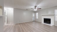 This single-floor, 1-bedroom, 1-bathroom residence offers a thoughtfully organized layout with a clean, neutral aesthetic throughout. The combined kitchen and living room forms the heart of the home, featuring light-toned luxury vinyl plank flooring, a textured ceiling, and a ceiling fan with integrated lighting. A white-mantled fireplace anchors the living area, adding warmth and character, while multiple windows dressed with horizontal blinds allow natural light to fill the space. A private entry door with a glass panel provides additional brightness.

The galley-style kitchen is efficiently designed with gray cabinetry, light countertops, and black stainless appliances including a refrigerator and range, all illuminated by an overhead flush-mount light fixture.

The spacious bedroom continues the consistent flooring and neutral palette, offering ample room for furnishings and direct access to a walk-in closet equipped with built-in shelving and hanging rods. The bathroom includes a tub/shower combination with white tile surround and stainless steel grab bars for added accessibility.

A dedicated in-unit laundry area houses a full-size top-load washer, and additional storage is available throughout. The cohesive design and functional layout make this a comfortable and practical living space.