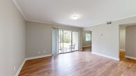 This single-floor residence at 7950 Shoals Drive in Orlando, Florida offers a well-designed layout with a clean, neutral aesthetic throughout. The open living area is a standout feature, showcasing warm wood-look flooring, crown molding, and abundant natural light streaming through large sliding glass doors that lead directly to an outdoor patio — a seamless connection to the lush greenery beyond. A secondary window further brightens the adjoining dining or flex space.

The kitchen is thoughtfully updated, featuring white shaker cabinetry, marble-look stone countertops, a deep undermount sink with a contemporary pull-down faucet, and stainless steel appliances including a refrigerator, range, microwave, and dishwasher. A pass-through counter opens the kitchen to the main living area, enhancing the sense of connectivity.

The bedrooms are carpeted for comfort, each offering built-in closets with wire shelving for practical storage. One bedroom includes a ceiling fan. The bathroom is finished with a wide white vanity, stone countertop, a large mirror, and wood-look flooring, providing a bright, clean retreat. Neutral warm-gray tones carry throughout, creating a cohesive and inviting atmosphere across the entire home.
