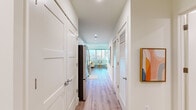 This thoughtfully designed single-floor residence offers a cohesive blend of modern aesthetics and practical functionality. The open-concept living area serves as the heart of the home, bathed in abundant natural light streaming through large floor-to-ceiling windows that frame views of the surrounding landscape. Light hardwood flooring flows continuously throughout, lending warmth and visual continuity to the space.

The galley-style kitchen is well-appointed with crisp white cabinetry, white quartz countertops, a subway tile backsplash, and a full suite of stainless steel appliances, including a refrigerator, range, microwave, and dishwasher. Ample upper and lower cabinetry provides generous storage throughout.

A welcoming entry corridor with louvered closet doors leads seamlessly into the living and dining areas. The bedroom features a walk-in closet and direct sightlines to the bright living space, creating an airy, connected feel. A dedicated workspace area near the windows offers an ideal setting for focused work or study.

The bathroom is finished with full-height white tile in the walk-in shower, a modern vanity with an undermount sink, and neutral tile flooring. Throughout the residence, recessed lighting, clean white walls, and contemporary hardware contribute to a polished, move-in-ready ambiance.