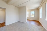 Located at 400 S Palm Dr in Novato, CA, this one-bedroom, one-bathroom residence offers a well-organized single-floor layout designed for comfortable everyday living. The open living and dining area is bathed in natural light from multiple large windows dressed with vertical blinds, offering pleasant outdoor views of the surrounding Novato landscape. Exposed ceiling beams add a subtle architectural character to the living space, which features a combination of plush carpet and warm wood-look flooring that transitions seamlessly into the kitchen and dining zone. The kitchen is equipped with light wood cabinetry, a built-in electric range, refrigerator, and a sink with ample counter space, complemented by a tall window that keeps the area bright and airy. The carpeted bedroom is a comfortable retreat, featuring two large windows with outdoor views, generous wall space, and a dedicated closet with built-in shelving and hanging rods. The full bathroom includes a wood-tone vanity with under-cabinet storage, a large wall mirror, a shower/tub combination, and warm wood-look flooring. Two hallways connect the rooms efficiently, and the overall neutral color palette creates a clean, inviting atmosphere throughout.
