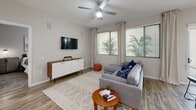 This well-appointed one-bedroom, one-bathroom model unit on the fourth floor at 4949 N 7th Street in Phoenix, Arizona offers a thoughtfully designed open layout with modern finishes throughout. Light wood-style flooring flows through the main living areas, complementing the neutral color palette and creating a cohesive, contemporary aesthetic.

The kitchen is a standout feature, boasting dark slate cabinetry extending to the ceiling, white quartz countertops, stainless steel appliances including a refrigerator, range, and microwave, and a peninsula with bar seating that connects seamlessly to the dining area. Track lighting overhead adds both function and style. A dedicated laundry room with a full-size washer and dryer is conveniently accessible from the kitchen.

The living room is bright and welcoming, with multiple windows allowing generous natural light and a ceiling fan overhead. A private balcony extends the living space outdoors, offering open views of the surrounding Phoenix skyline.

The carpeted bedroom is generously sized, featuring a ceiling fan, a large window, and direct access to a walk-in closet with built-in shelving. The bathroom is finished with dark wood-tone cabinetry, a white countertop vanity, a framed mirror, and wood-style flooring, delivering a clean and modern feel throughout.