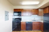 Located at Seay Street in Alexandria, VA, this 2-bedroom, 1-bathroom residence offers a well-organized, single-floor layout designed for comfortable everyday living. The living room is bright and open, showcasing warm hardwood flooring and a full-height sliding glass door that leads to a private balcony overlooking lush outdoor scenery — an ideal spot for natural light and fresh air. The space flows naturally into a combined dining and kitchen area, where rich warm-toned wood cabinetry pairs with black appliances, including a gas range, built-in microwave, dishwasher, and refrigerator, all set above hardwood floors and beneath a flush ceiling light fixture. A hallway connects the main living areas to the two bedrooms and shared bathroom. The primary bedroom is generously sized, featuring plush carpeting and a window with a view of the surrounding neighborhood. The second bedroom offers hardwood floors and a bright window, providing flexibility for a guest room or home office. Four closets throughout the unit ensure ample storage. The full bathroom features a soaking tub with a tiled surround accented by a decorative taupe-and-white checkered border, complemented by a wood vanity with a white countertop. The overall aesthetic is clean and neutral throughout.
