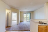 This single-story, one-bedroom, one-bathroom unit in San Jose, California offers a well-organized layout that makes efficient use of its compact footprint. The open-concept living and dining area is carpeted and bathed in natural light, drawing the eye toward a sliding glass door that opens onto a private balcony overlooking lush greenery — a standout feature that brings an outdoor connection to the interior.

The kitchen is positioned adjacent to the living area and features warm honey-toned wood cabinetry extending to the upper walls, a peninsula with a built-in sink, light countertops, tile flooring, a white electric range, and a full-size refrigerator. Overhead lighting illuminates the space effectively.

The bedroom is a comfortable, well-proportioned room with plush carpeting, neutral walls, and dual windows that invite ample natural light. A closet with sliding doors and built-in shelving and hanging rod provides organized storage.

The bathroom includes a full tub-shower combination, a wood-cabinet vanity with a sink, a toilet, and tile flooring, all finished in light, neutral tones that keep the space feeling clean and functional.

Overall, the unit presents a bright, neutral palette throughout, creating a cohesive and livable environment in the heart of San Jose.