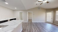Located at 500 Napa Valley Dr in Little Rock, Arkansas, this single-story, one-bedroom, one-bathroom home offers a well-designed layout with modern finishes throughout. The open-concept kitchen and living area is highlighted by dramatic vaulted ceilings and a ceiling fan, creating an airy, spacious feel. The kitchen is equipped with dark shaker-style cabinetry, black appliances including a refrigerator, range, and microwave, and striking marble-look countertops that extend generously along the wall, providing ample prep and workspace. A peninsula with a sink and matching countertop adds additional functionality. Light wood-look flooring runs throughout the main living areas, complementing the neutral warm-beige walls. The living area benefits from a private exterior door and large windows fitted with blinds, allowing for abundant natural light. The bedroom features plush carpeting, a ceiling fan, and a large window, offering a comfortable retreat. The bathroom is finished with large marble-look wall tiles surrounding a tub-shower combination and matching wood-look flooring. A dedicated laundry area with a full-size washer and dryer rounds out this practical and stylish home.