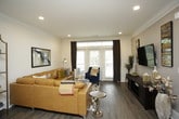This thoughtfully designed single-floor residence offers a harmonious blend of modern finishes and comfortable living spaces. The open-concept living room is anchored by wood-look flooring, crown molding, and recessed lighting, creating a warm and inviting atmosphere. Large sliding glass doors flood the space with natural light and provide access to an outdoor balcony, while elegant draping and a bold geometric area rug add stylish character to the room.

The kitchen is a standout feature, showcasing white shaker-style cabinetry extending to the ceiling, a classic subway tile backsplash, and dark granite countertops. A two-toned central island with quartz countertop and bar seating serves as both a functional workspace and gathering spot, complemented by pendant lighting overhead. Stainless steel appliances, including a French door refrigerator, complete this chef-ready space.

The primary bedroom offers a serene retreat with plush carpeting, a ceiling fan, and generous natural light through large windows. Its en-suite bathroom is well-equipped with a dual-sink vanity, a soaking tub, a separate glass-enclosed shower, tile flooring, and direct access to a spacious walk-in closet. A second bedroom mirrors the comfort and style of the primary, also featuring a ceiling fan and ample natural light.