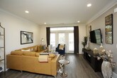 This thoughtfully designed single-floor residence offers a harmonious blend of modern finishes and comfortable living spaces. The open-concept living room is anchored by wood-look flooring, crown molding, and recessed lighting, creating a warm and inviting atmosphere. Large sliding glass doors flood the space with natural light and provide access to an outdoor balcony, while elegant draping and a bold geometric area rug add stylish character to the room.

The kitchen is a standout feature, showcasing white shaker-style cabinetry extending to the ceiling, a classic subway tile backsplash, and dark granite countertops. A two-toned central island with quartz countertop and bar seating serves as both a functional workspace and gathering spot, complemented by pendant lighting overhead. Stainless steel appliances, including a French door refrigerator, complete this chef-ready space.

The primary bedroom offers a serene retreat with plush carpeting, a ceiling fan, and generous natural light through large windows. Its en-suite bathroom is well-equipped with a dual-sink vanity, a soaking tub, a separate glass-enclosed shower, tile flooring, and direct access to a spacious walk-in closet. A second bedroom mirrors the comfort and style of the primary, also featuring a ceiling fan and ample natural light.
