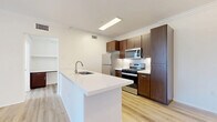 This well-appointed one-bedroom, one-bathroom unit in Rancho Cucamonga, CA offers a thoughtfully designed, single-floor layout that maximizes functionality and comfort. The open-concept kitchen and living area serves as the heart of the home, anchored by a large white quartz peninsula with an undermount sink — ideal for both meal prep and casual dining. Rich dark-brown cabinetry provides ample storage, while a full suite of stainless steel appliances, including a gas range, over-the-range microwave, and refrigerator, completes the kitchen. Light wood-style luxury flooring runs throughout the entire unit, creating a cohesive and bright aesthetic. Crown molding adds a refined architectural touch to the living area, which also features a ceiling fan and sliding glass doors that open onto a private patio with outdoor views. The bedroom is a comfortable, well-proportioned space with a window framing natural light and views of the surrounding greenery, complemented by a dedicated closet. The full bathroom features a dark-wood vanity with white countertop, a backlit mirror, and a shower-tub combination. A hallway connects all areas efficiently, completing this clean, modern layout.