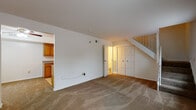 This two-story residence offers a practical and well-organized layout across both floors. The main level centers around a spacious carpeted living area that features a staircase leading to the upper floor, built-in double closets for ample storage, and direct access to a full bathroom equipped with a tub and shower combination. The galley-style kitchen is efficiently designed with warm honey-toned oak cabinetry, granite-look countertops, a gas range with oven, over-the-range microwave, refrigerator, and a double sink — all finished with easy-care tile flooring. A dedicated utility area off the kitchen houses a stacked washer and dryer unit alongside the water heater, providing convenient in-unit laundry. The upper floor hosts a generously sized bedroom with plush carpet flooring and two windows that allow natural light to fill the room while offering views of the surrounding neighborhood. Throughout the residence, clean white walls and neutral tones create a bright, versatile backdrop ready for personalization. The thoughtful two-floor design maximizes privacy and separation between living and sleeping spaces, making this a functional and comfortable home.