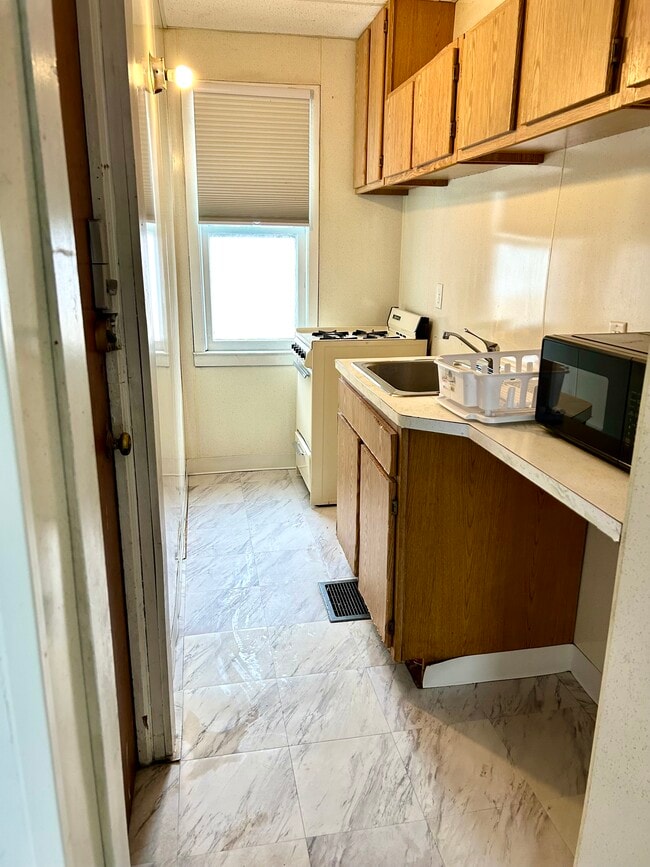 Galley Kitchen with stove, refrigerator and microwave - 584 Ridge Rd