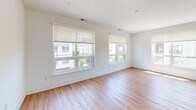 This thoughtfully designed 2-bedroom, 2-bathroom residence at 100 S Washington Ave offers a clean, modern aesthetic across a well-proportioned single-floor layout. The open-concept living and kitchen area serves as the heart of the home, featuring warm hardwood-style flooring, crisp white walls, and multiple large windows fitted with roller shades that bathe the space in natural light and offer views of the surrounding neighborhood. The kitchen is a standout feature, showcasing white shaker cabinetry, dark stone countertops, a subway tile backsplash, stainless steel appliances including a gas range, microwave, and refrigerator, and a central island with pendant lighting — ideal for both cooking and entertaining. In-unit stacked laundry adds everyday convenience. The spacious primary bedroom offers generous proportions with dual windows and ample natural light, while the second bedroom also features a window with an outdoor view. Both rooms continue the hardwood-style flooring found throughout. The bathrooms are finished with a clean, contemporary style — one features a glass-enclosed walk-in shower with full white subway tile surround and built-in shelving, while the second includes a wood-toned wall cabinet for added storage. The overall ambiance is bright, minimal, and move-in ready.