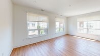 This thoughtfully designed 2-bedroom, 2-bathroom residence at 100 S Washington Ave offers a clean, modern aesthetic across a well-proportioned single-floor layout. The open-concept living and kitchen area serves as the heart of the home, featuring warm hardwood-style flooring, crisp white walls, and multiple large windows fitted with roller shades that bathe the space in natural light and offer views of the surrounding neighborhood. The kitchen is a standout feature, showcasing white shaker cabinetry, dark stone countertops, a subway tile backsplash, stainless steel appliances including a gas range, microwave, and refrigerator, and a central island with pendant lighting — ideal for both cooking and entertaining. In-unit stacked laundry adds everyday convenience. The spacious primary bedroom offers generous proportions with dual windows and ample natural light, while the second bedroom also features a window with an outdoor view. Both rooms continue the hardwood-style flooring found throughout. The bathrooms are finished with a clean, contemporary style — one features a glass-enclosed walk-in shower with full white subway tile surround and built-in shelving, while the second includes a wood-toned wall cabinet for added storage. The overall ambiance is bright, minimal, and move-in ready.