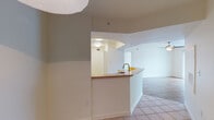 This single-floor residence offers a practical and functional layout connecting key living areas in a cohesive open-concept design. The kitchen serves as a central feature, equipped with light wood cabinetry, patterned laminate countertops, a double-basin stainless steel sink, a coil-burner electric range, a built-in dishwasher, and an overhead range hood. A peninsula with a wraparound counter extends into the adjoining space, providing additional prep area while visually connecting the kitchen to the living area. Tile flooring runs throughout the kitchen and entry areas, transitioning to carpet in the living and bedroom spaces.

The living area is bright and open, featuring a ceiling fan and neutral wall tones that contribute to a clean, understated ambiance. The bedrooms are carpeted and receive natural light through large windows fitted with horizontal blinds, offering views of the surrounding greenery. The layout, visible in the 3D overview, reveals multiple rooms arranged efficiently around a central corridor.

Two full bathrooms each include a tub-shower combination with white tile surrounds and standard fixtures, maintaining a consistent, clean aesthetic throughout the unit. Overall, the space presents a straightforward, well-organized floor plan suited for everyday living.