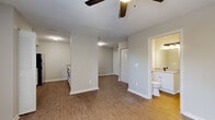 This single-floor unit offers a clean, modern aesthetic throughout, highlighted by warm wood-look flooring and a neutral color palette that creates a bright and cohesive atmosphere. The open-concept living area is anchored by a ceiling fan and receives natural light through a large window, offering pleasant outdoor views. A pass-through peninsula counter connects the living space to the kitchen, creating an easy flow between the two areas. The kitchen is well-equipped with stainless steel appliances — including a refrigerator, electric range, microwave, and dishwasher — complemented by crisp white cabinetry with matte black hardware and a double-basin sink. A washer unit is also conveniently tucked within the kitchen area. The bedroom is generously sized, featuring a ceiling fan with light fixture, a louvered bi-fold closet, and a window that brings in natural light. The bathroom is finished with a white shaker-style vanity, a light stone-look countertop, a large mirror with a modern three-bulb vanity light, and matte black fixtures that add a contemporary touch. An electrical panel is accessible near the entry area. Throughout the unit, clean white trim and consistent flooring tie all spaces together for a polished, move-in-ready feel.