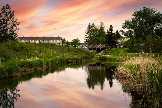 Small creek in a community recreation area with a sunset reflecting on the water at Nose Creek Park in Airdrie, Alberta.