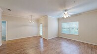 Located at 9905 Windsor Club Dr in Riverview, FL, this well-appointed single-floor residence offers a thoughtfully designed layout across a comfortable footprint. The combined living and dining area serves as the heart of the home, showcasing warm wood-look laminate flooring, crown molding, and a ceiling fan that adds both style and function. A chandelier distinguishes the dining area, while a large window fills the space with natural light and offers outdoor views. The kitchen features warm wood cabinetry, a tile backsplash, a breakfast bar with a light stone-finish countertop, and white appliances including a refrigerator, electric range, and built-in microwave — all complemented by tile flooring. The bedroom is generously sized with plush carpet, crown molding, a ceiling fan, and a window for natural light. Four closets provide ample storage throughout the unit. The bathroom includes a white vanity with storage drawers, a framed mirror, and updated lighting fixtures. A dedicated laundry room houses a full-size washer and dryer with overhead shelving for convenience. The space also includes a private patio, extending the living area outdoors — a welcome feature in the warm Florida climate.