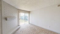 Located at 12000 Fleming Dr in Houston, TX 77070, this single-floor, 2-bedroom, 1-bathroom home offers a practical and functional layout. The galley-style kitchen is a standout feature, showcasing light wood-look flooring, white cabinetry, white countertops, and black appliances including a range, refrigerator, and dishwasher, all beneath recessed lighting. A hallway connects the main living areas to the bedrooms and shared bathroom, providing a logical flow throughout the home. The primary bedroom is a generously sized retreat with soft carpet flooring, a textured ceiling, and a window with blinds that allows natural light to filter in. It also benefits from direct access to a dedicated walk-in closet, which is outfitted with dual wire shelving units and additional carpet flooring — offering ample storage. The second bedroom mirrors the primary in finish, featuring the same carpet, a textured ceiling, a ceiling fan with light fixture, and a window for natural light. The full bathroom is clean and straightforward, equipped with a white tiled tub and shower combination, a toilet, and a towel bar. The home's neutral color palette and consistent finishes throughout create a cohesive, move-in ready atmosphere.