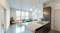 This contemporary single-floor residence showcases a thoughtfully designed open-concept layout that seamlessly connects the kitchen, dining, and living areas. The kitchen is a standout feature, equipped with dark espresso cabinetry, granite countertops, stainless steel appliances, and a spacious island with a double sink and bar seating — all illuminated by a trio of modern pendant lights that add a refined touch. The living area benefits from soaring ceilings, a ceiling fan, and multiple large windows fitted with horizontal blinds that invite abundant natural light while maintaining privacy.

Polished concrete floors flow throughout the space, providing a clean, modern aesthetic that ties each room together. The residence includes multiple bedrooms, each featuring ceiling fans, large windows with outdoor views, and generous proportions. The primary bedroom offers a calm, well-lit retreat with ample wall space and natural light filtering in through the windows.

The bathrooms are well-appointed with granite-topped dark cabinetry vanities, polished concrete floors, and full shower and tub fixtures. One bathroom includes convenient access to a walk-in closet, adding practical storage to the space. Overall, the residence presents a cohesive modern design with high-quality finishes and functional, comfortable living spaces.