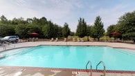 Situated along Highway 57 in Ocean Springs, Mississippi, this single-story property offers a welcoming and well-maintained environment with notable outdoor amenities. The standout feature of the property is its generously sized outdoor swimming pool, which showcases clear turquoise water and a classic brick-edged surround. The pool area is thoughtfully appointed with multiple lounge chairs positioned along the perimeter, providing ample space for relaxation. A shaded seating area with a distinctive red umbrella adds a practical and inviting touch for guests seeking refuge from the sun. The pool is enclosed by a wrought-iron style fence, ensuring both safety and an open, airy feel. Beyond the fence, a backdrop of mature deciduous trees creates a natural, park-like setting that enhances the overall ambiance of the outdoor space. The lush greenery provides a sense of privacy while maintaining a connection to the surrounding natural landscape. The property's single-floor layout contributes to an accessible and cohesive design, making it a functional and pleasant space suited for a variety of uses. Its location in Ocean Springs places it within a vibrant Mississippi Gulf Coast community known for its natural beauty and welcoming character.