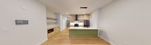 This contemporary apartment offers 1130 square feet of thoughtfully designed living space on a single floor. The layout includes two bedrooms, two bathrooms, a hallway, and an open-concept kitchen and living room area. The primary bedroom is generously sized at 210 square feet, providing ample space for comfort and relaxation.

The interior is characterized by clean lines and a neutral color palette, creating a fresh and inviting atmosphere. Light wood-toned flooring runs throughout the apartment, adding warmth and continuity to the space. The living area is bright and airy, featuring large windows that allow natural light to flood the room and offer views of the outdoors.

The kitchen is a standout feature, boasting modern light wood cabinetry, stainless steel appliances, and a striking white quartz countertop. A unique green-fronted island adds a pop of color and serves as both a functional workspace and casual dining area. Stylish pendant lighting enhances the overall aesthetic.

Both bathrooms are elegantly appointed with contemporary fixtures, including glass shower enclosures and wooden vanities. The floors feature a distinctive terrazzo-style tile, adding visual interest to these spaces.

Storage solutions are thoughtfully integrated throughout the apartment, including built-in closet systems. The overall design emphasizes functionality without compromising on style, making this apartment an ideal urban living space.