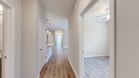 Located at 4039 W Village Pkwy in Ellenwood, GA, this single-story, three-bedroom, two-bathroom home offers a clean, modern layout designed for comfortable everyday living. Light-toned luxury vinyl plank flooring runs consistently throughout the home, providing a cohesive and low-maintenance foundation in every room.

A central hallway connects the main living areas, with pendant lighting overhead and easy access to all three bedrooms. The living room is bright and open, featuring a ceiling fan and French doors that invite natural light and provide outdoor access. The kitchen is efficiently designed with gray shaker-style cabinetry, granite countertops, and black appliances including a refrigerator, range, and built-in microwave.

Each bedroom is finished with the same warm flooring, ceiling fans, and windows that bring in natural light and outdoor views. The primary bedroom includes a walk-in closet with wire shelving for organized storage. Both bathrooms feature gray vanity cabinets with granite countertops and undermount sinks. One bathroom includes a tiled walk-in shower, while the second offers a clean, functional layout with a large mirror. Three closets total provide ample storage throughout the home.