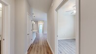 Located at 4039 W Village Pkwy in Ellenwood, GA, this single-story, three-bedroom, two-bathroom home offers a clean, modern layout designed for comfortable everyday living. Light-toned luxury vinyl plank flooring runs consistently throughout the home, providing a cohesive and low-maintenance foundation in every room.

A central hallway connects the main living areas, with pendant lighting overhead and easy access to all three bedrooms. The living room is bright and open, featuring a ceiling fan and French doors that invite natural light and provide outdoor access. The kitchen is efficiently designed with gray shaker-style cabinetry, granite countertops, and black appliances including a refrigerator, range, and built-in microwave.

Each bedroom is finished with the same warm flooring, ceiling fans, and windows that bring in natural light and outdoor views. The primary bedroom includes a walk-in closet with wire shelving for organized storage. Both bathrooms feature gray vanity cabinets with granite countertops and undermount sinks. One bathroom includes a tiled walk-in shower, while the second offers a clean, functional layout with a large mirror. Three closets total provide ample storage throughout the home.