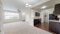 Located at 1020 Aspen Pines Dr in Wilder, KY, this well-appointed 2-bedroom, 2-bathroom single-floor home offers a thoughtfully designed layout across a comfortable footprint. The open-concept living and dining area flows seamlessly into the kitchen, creating an inviting shared space ideal for everyday living. The kitchen is outfitted with rich dark cabinetry, granite countertops, a stainless steel sink, and matching dark appliances, including a dishwasher and range, all set atop rich hardwood-style flooring. A decorative chandelier illuminates the dining area, while a ceiling fan keeps the living room comfortable year-round. Large windows throughout the home allow ample natural light to fill each room. Both bedrooms feature plush wall-to-wall carpeting and ceiling fans, with the primary bedroom offering generous dimensions and access to a spacious walk-in closet outfitted with wire shelving on three sides. Each bathroom is finished with dark wood vanities, granite countertops, and hardwood-style flooring, with tub-shower combinations providing practical functionality. Crown molding accents add a refined architectural touch to the main living areas. A utility room and hallway complete the layout, offering additional convenience and storage within this clean, move-in-ready home.