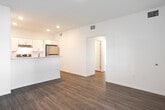 Located at 915 Ariana St in Lakeland, Florida, this single-story residence offers a clean, modern aesthetic highlighted by wood-look plank flooring that flows seamlessly throughout the entire space. The open-concept living and dining area is bright and airy, with recessed lighting and a neutral color palette that creates a welcoming atmosphere. A peninsula-style kitchen opens directly to the living area and is equipped with white shaker cabinetry, granite-look countertops, a stainless steel refrigerator, a stainless steel range, and an under-cabinet range hood — providing both style and functionality. A dedicated pantry closet with built-in shelving offers generous additional storage. The bedrooms are well-proportioned, with large windows that bring in natural light, and at least one features a closet with a sliding door. The bathroom is finished with a white shaker vanity, granite-look countertop, a framed mirror, wood-look tile flooring, and a full tub-shower combination with tile surround. The overall design emphasizes a fresh, move-in-ready condition with consistent modern finishes across every room, making this a well-appointed and functional single-floor residence.